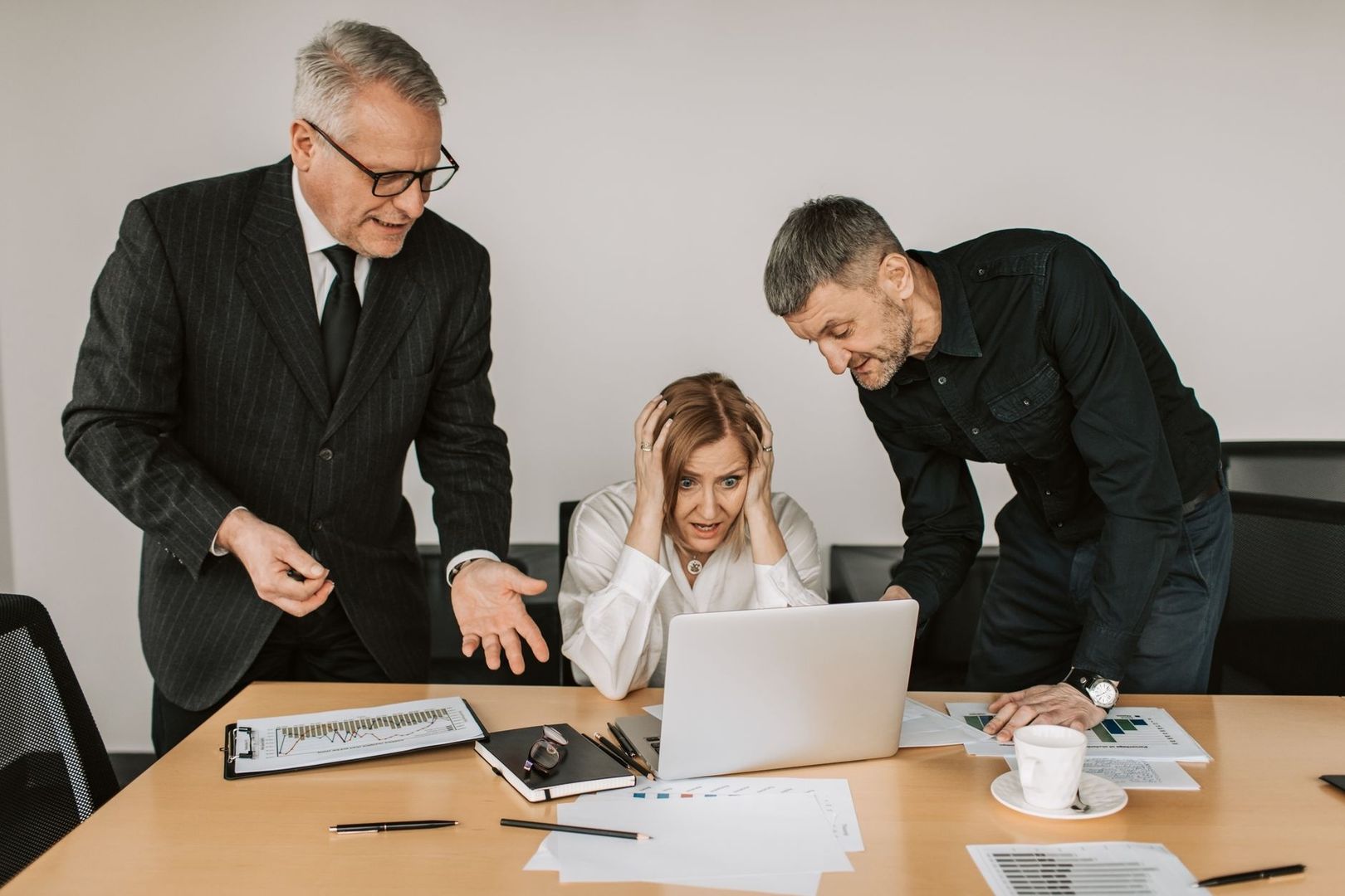 Stressat team diskuterar kris vid laptop och analyser på ett möte